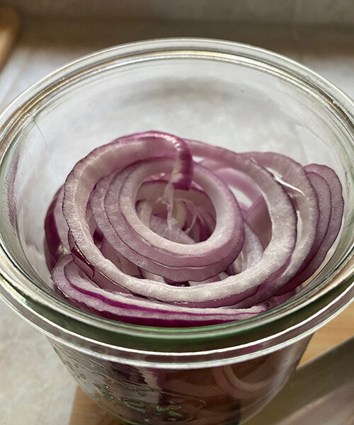 sliced red onions in a jar